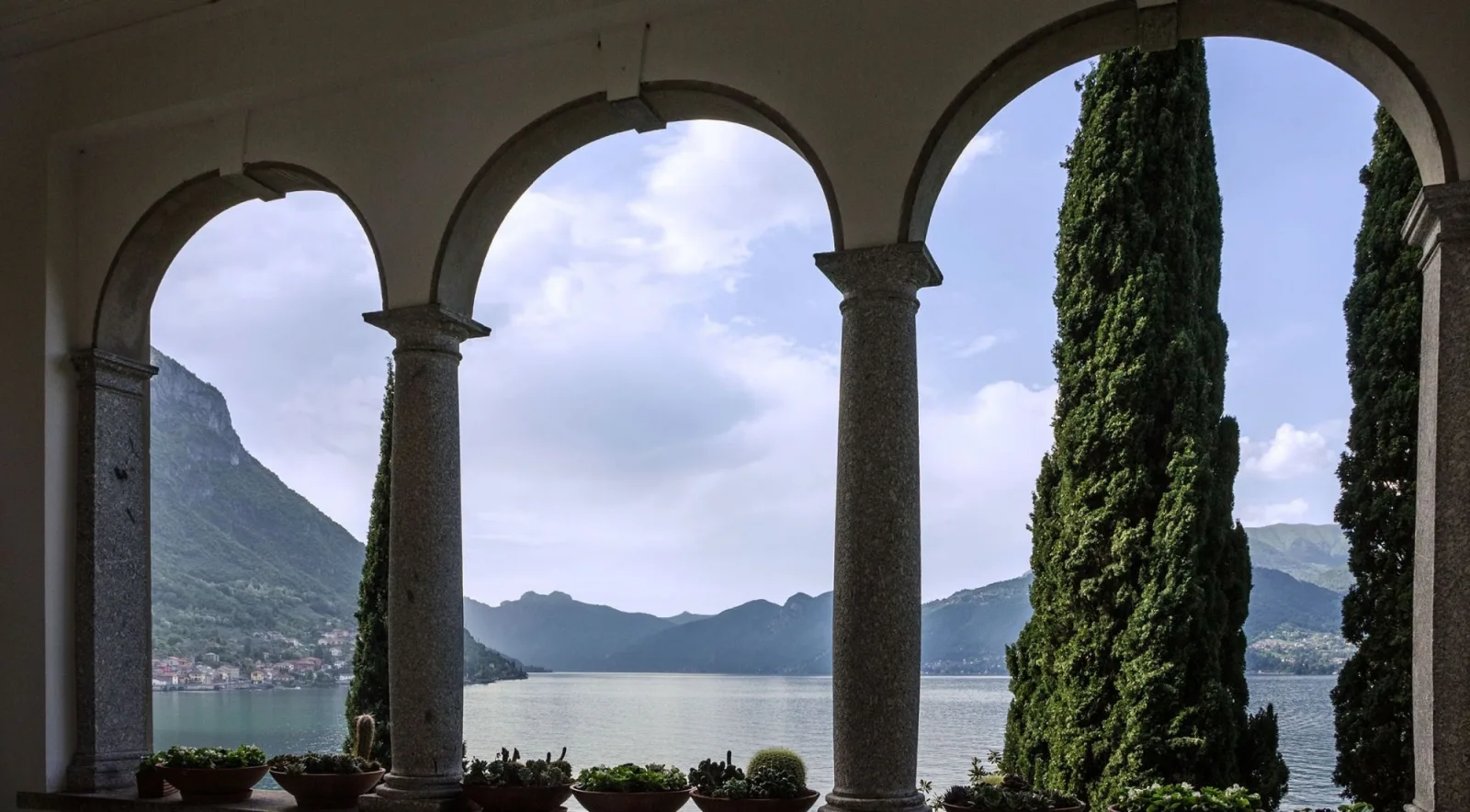 Granite columns and round arches of the Villa Monastero loggia framing the lake and the far shore