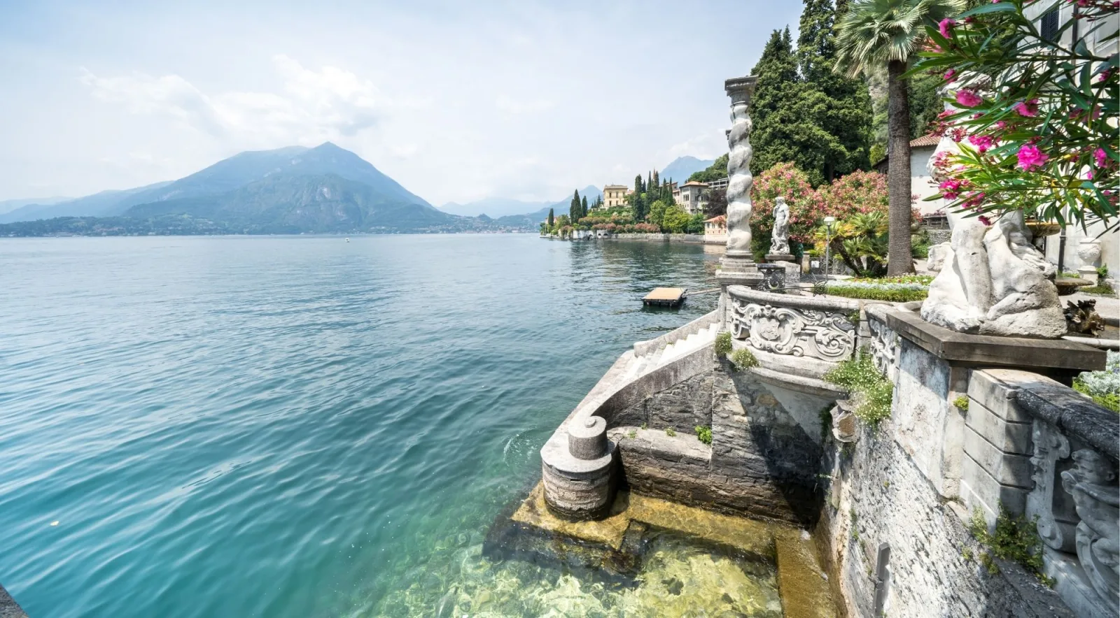 Carved baroque balustrade and a curving stone stair descending to the water at Villa Monastero