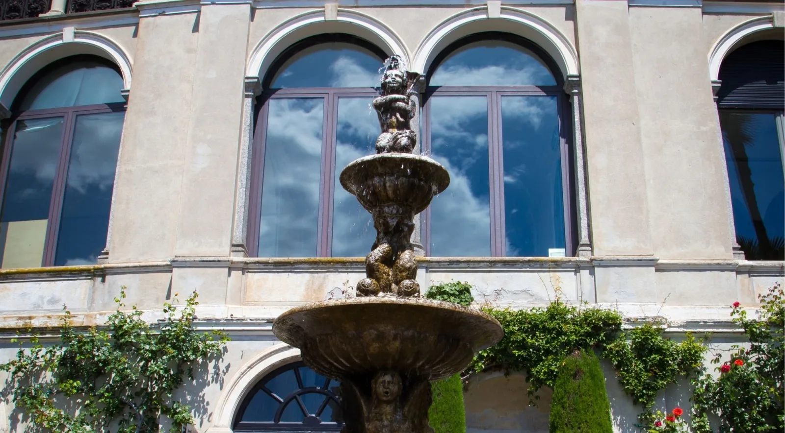Tiered cherub fountain playing in front of the arched windows of Villa Monastero