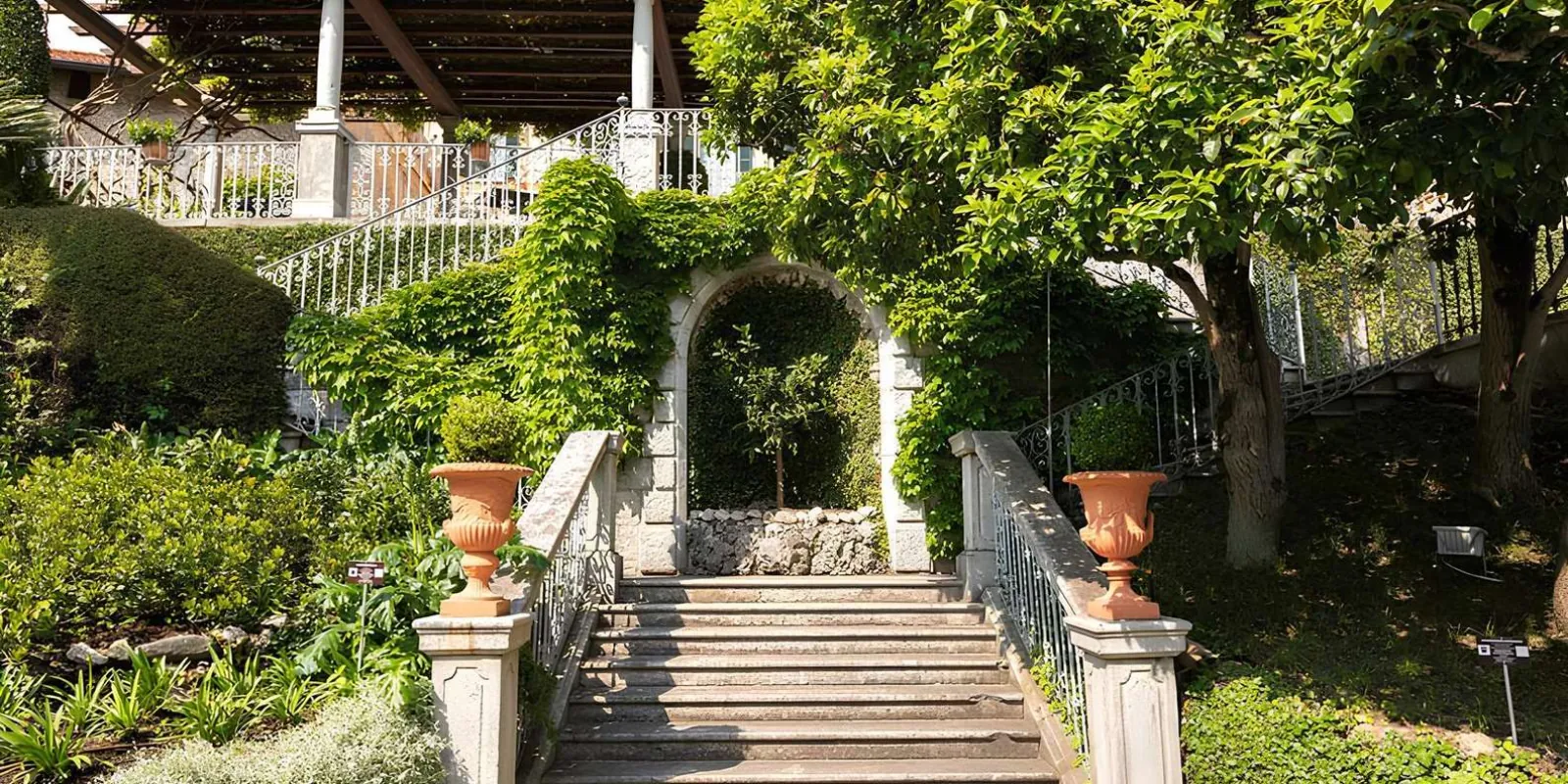 The stepped garden stair at Villa Cipressi, terracotta urns either side and a vine-covered arch above