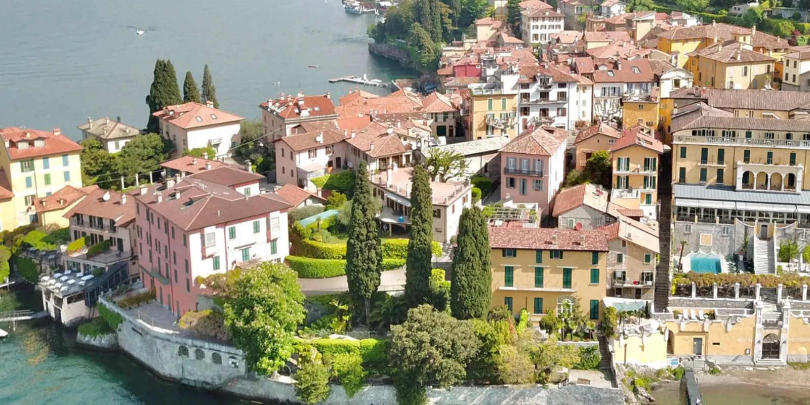Varenna from above — cypresses, terracotta roofs and the villa terraces along the shore