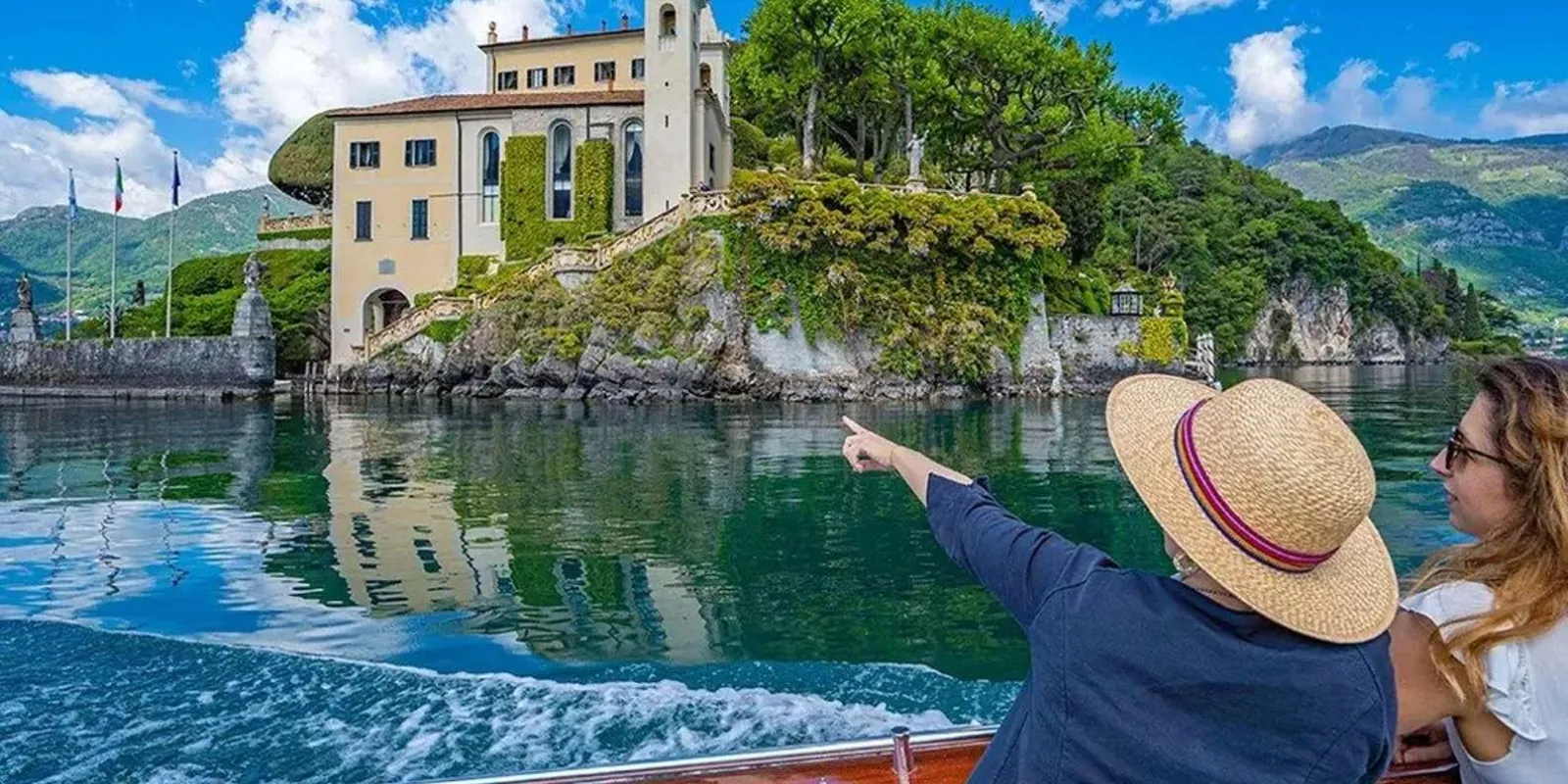 Passengers on the boat pointing at Villa del Balbianello as it comes into view on the promontory