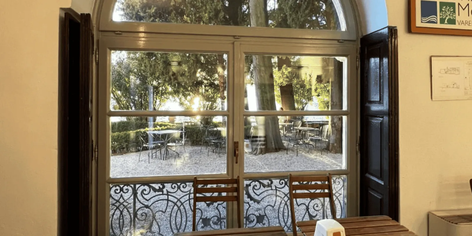 Inside the Villa Monastero bar, an arched window looking out to the gravel terrace and its tables