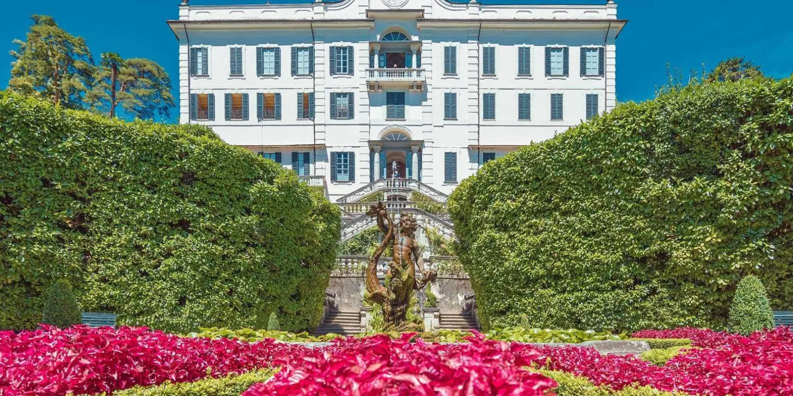 Villa Carlotta's white front above its clipped hedges and beds of massed pink flowers